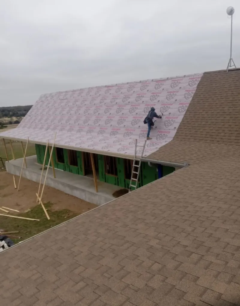 Worker preparing underlayment for a metal roof installation in Devils Lake